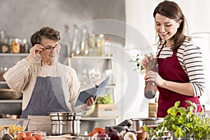 Grandmother reading recipe from cookbook