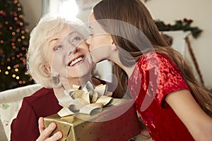 Grandmother Receiving Christmas Gift From Granddaughter At Home