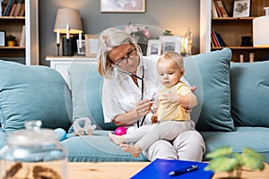 Grandmother retired woman doctor pediatric using stethoscope listening her grandson or granddaughter, young baby child lungs to