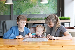 Grandmother`s daughter and granddaughter watching the menu in a cafe