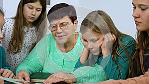 Grandmother showing old photo album to her four granddaughters