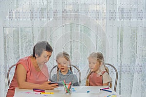 grandmother shows two granddaughters a drawing lesson on the phone home