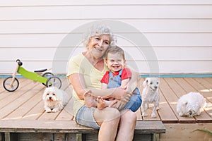 Grandmother sitting with grandson boy on porch at home backyard. Bonding of relatives and generation communication. Old woman with