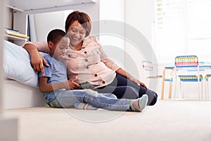 Grandmother Sitting With Grandson In Childs Bedroom Using Digital Tablet Together