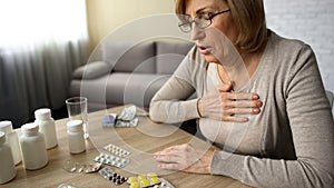 Grandmother suffering heart decease, drinking prescribed pills, feeling unwell photo