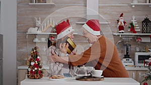 Grandmother suprising granddaughter with wrapper present gift during traditional winter holiday