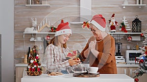 Grandmother suprising granddaughter with wrapper present gift during traditional winter holiday