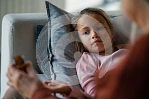 Grandmother taking care of her ill grandchild lying on sofa