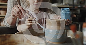 Grandmother teaches her granddaughter working on a pottery rotating wheel