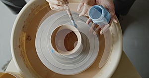 Grandmother teaches her granddaughter working on a pottery rotating wheel