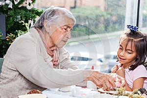 Grandmother teaching her granddaughter how to make christmas Nativity crafts