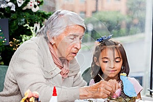 Grandmother teaching her granddaughter how to make christmas Nativity crafts
