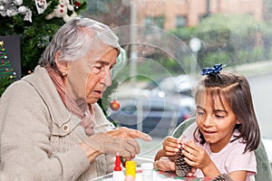 Grandmother teaching her granddaughter how to make christmas Nativity crafts