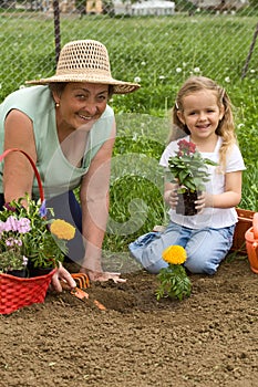 Grandmother teaching little girl gardening