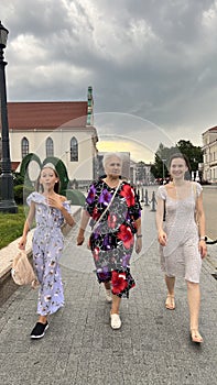 Grandmother and two granddaughters are walking around the city on the street.
