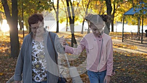 Grandmother walking with her granddaughter in the city Park at sunset.