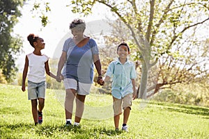 Grandmother Walking In Park And Holding Hands With Grandchildren photo