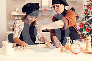 Grandmother wearing apron on christmas day spreading flour