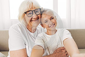 Grandmother woman child granddaughter happy hugging home sofa couch family girl love
