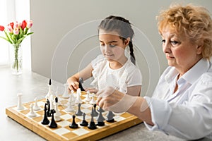 Grandmother and young girl playing chess together at home