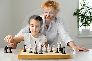 Grandmother and young girl playing chess together at home