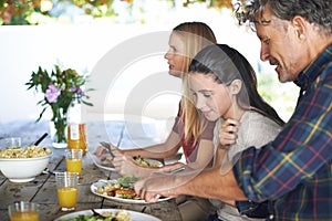 Grandpa can cut that for you. a family to eating lunch together outdoors.