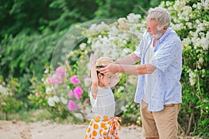 Grandpa dressed up hat to grandchildren little girl during holiday trip at park flower field looks cute lovely and warm