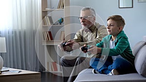 Grandpa and grandson playing video game with console, happy time together