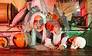 Grandpa and grandson with pumpkin together as preparation for Halloween. Dad and his kid in carnival costumes on