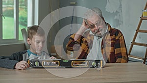 Grandpa and grandson are studying the principle of operation of the water level. A teenager examines the instrument with