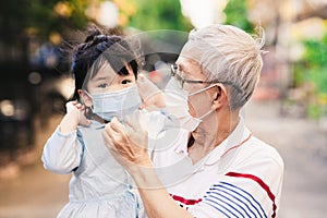 Grandpa is helping to provide a medical face mask for granddaughter to prevent contagion of coronavirus and dust PM 2.5.