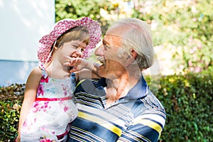 Grandpa and his granddaughter laughing outdoors photo