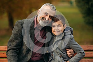 Grandpa and his grandson spend time together in the park. They are sitting on the bench. Walking in the park and