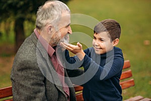 Grandpa and his grandson spend time together in the park. They are sitting on the bench. Walking in the park and