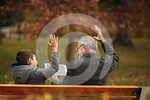 Grandpa and his grandson spend time together in the park. They are sitting on the bench. Walking in the park and