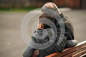 Grandpa and his grandson spend time together in the park. They are sitting on the bench. Walking in the park and