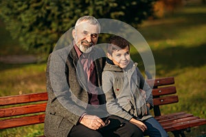 Grandpa and his grandson spend time together in the park. They are sitting on the bench. Walking in the park and