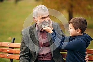 Grandpa and his grandson spend time together in the park. They are sitting on the bench. Walking in the park and