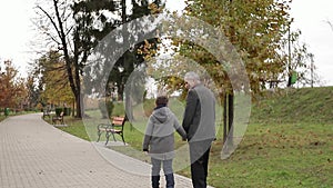 Grandpa and his grandson spend time together in the park. They are Walking in the park and rejoicing