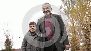 Grandpa and his grandson spend time together in the park. They are Walking in the park and rejoicing