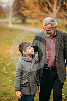 Grandpa and his grandson are walking in the park. The spend time together
