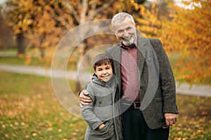 Grandpa and his grandson are walking in the park. The spend time together