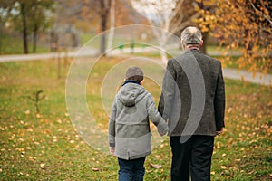 Grandpa and his grandson are walking in the park. The spend time together