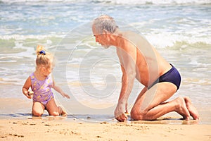 Grandpa Little Girl Sit on Wet Sand Look at Shell by Surf