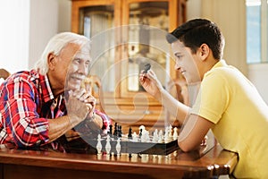 Grandpa Playing Chess Board Game With Grandson At Home photo