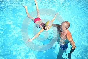 Grandpa teaches granddaughter to swim in the