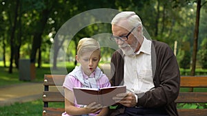 Grandpa teaches grandson to read book, encourages boy to knowledge, education