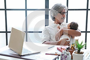 Grandpa using laptop while grandson reading newspaper