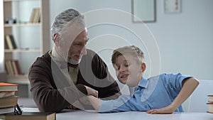 Grandpa winning in arm wrestling with grandson, proud of kid, family leisure