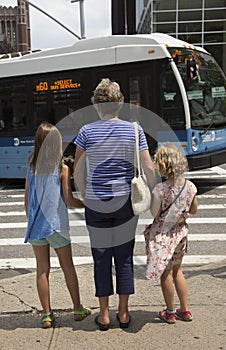 Grandparent with children wait to cross street